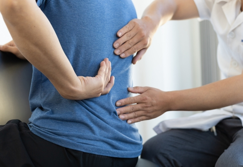 Chiropractor assessing a patient's back posture and movement during a chiropractic consultation